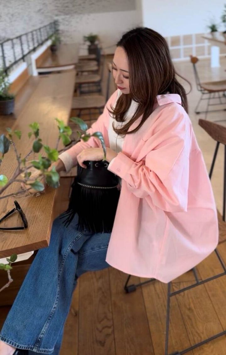 coca シャツ ピンク デニム×黒バッグ大人カジュアルコーデ カフェ座り