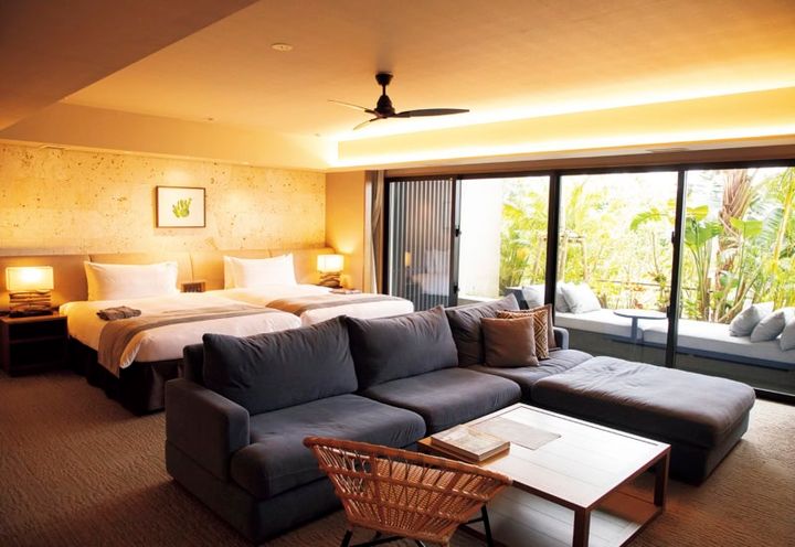 グランディスタイル 沖縄読谷ホテル＆リゾート。78平米のグランディスイート。ゆったりしたL字ソファに加え、テラスには特大のデイベッドもあり、ラウンジから戻ったらお昼寝タイムにしても。ベッドはシモンズで極上の寝心地。