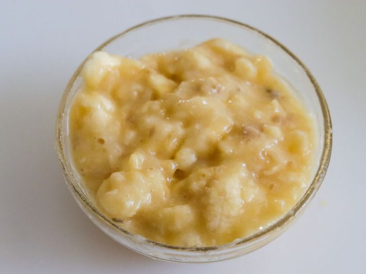 ガラスボウルでフォークを使い粗くつぶしたバナナ