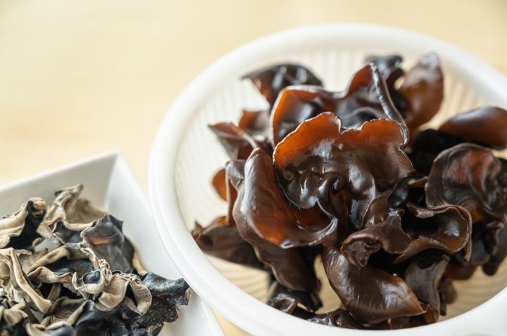 水で戻したキクラゲがザルに入っている 背景に乾燥きくらげ