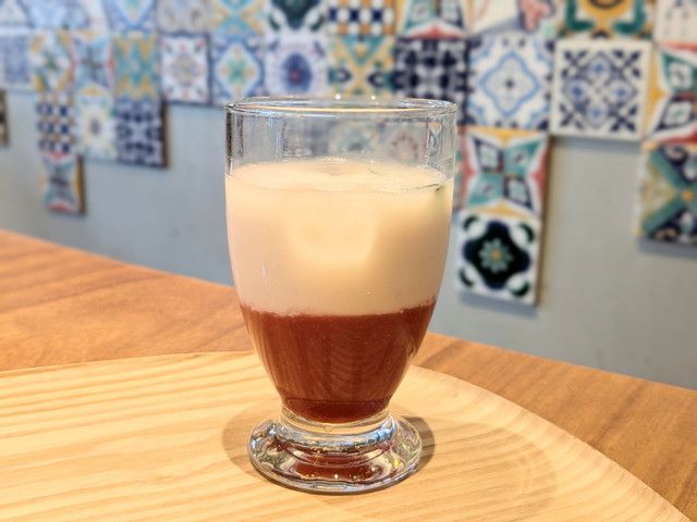 グラス底に赤いいちごソース、上にアーモンドミルクが重なった鮮やかな二層のドリンク