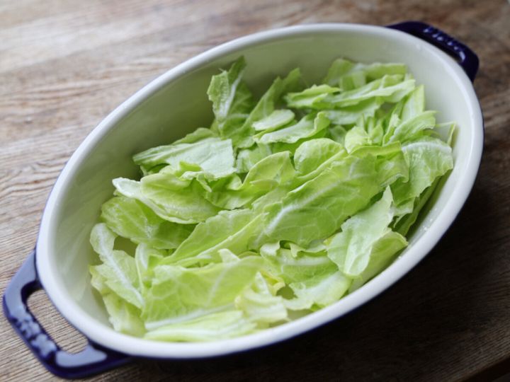 オーバルの耐熱容器の底に手でちぎった春キャベツを平らに敷き詰めた様子