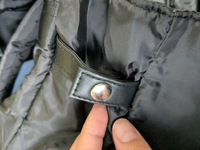 リュック側面のレザー調タブとシルバーのスナップボタンのアップ