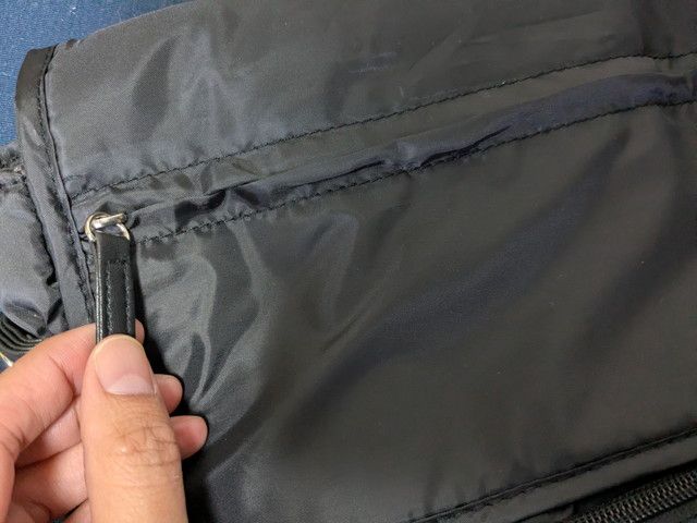 リュック前面上部のファスナーポケットのアップ。革風の引き手がついている