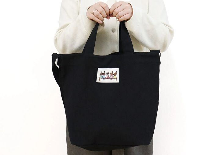 MOOMINのリトルミイ柄ワッペン付き黒ショルダーバッグを手持ちする女性