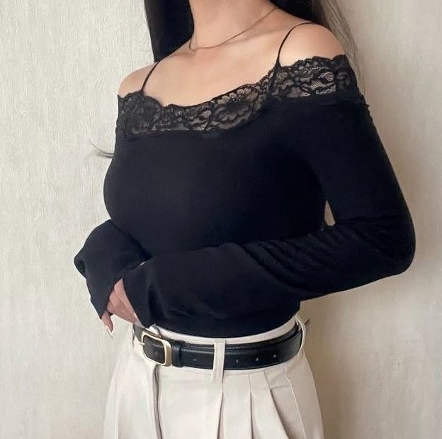 ブラックのオフショルダーニットトップス。胸元にレーストリムがあしらわれ、ホワイトワイドパンツとベルトを合わせたコーデ