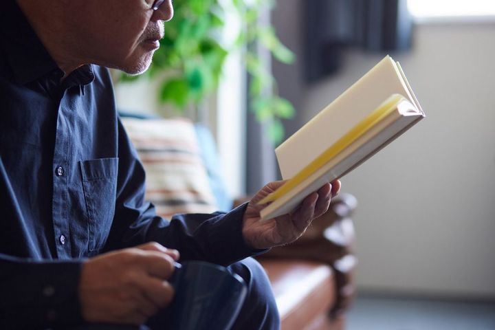 リビングで本を読む高齢男性