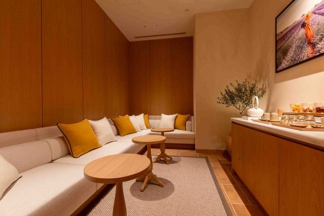 SPA L'OCCITANE EN PROVENCEのリラクゼーションルーム。イエローのクッションが並ぶソファとハーブティーコーナー