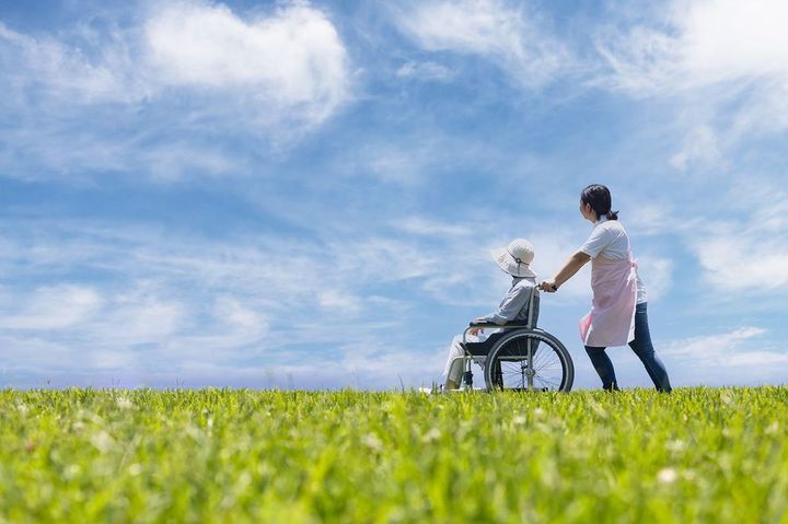 青空の下を散歩する2台の車椅子