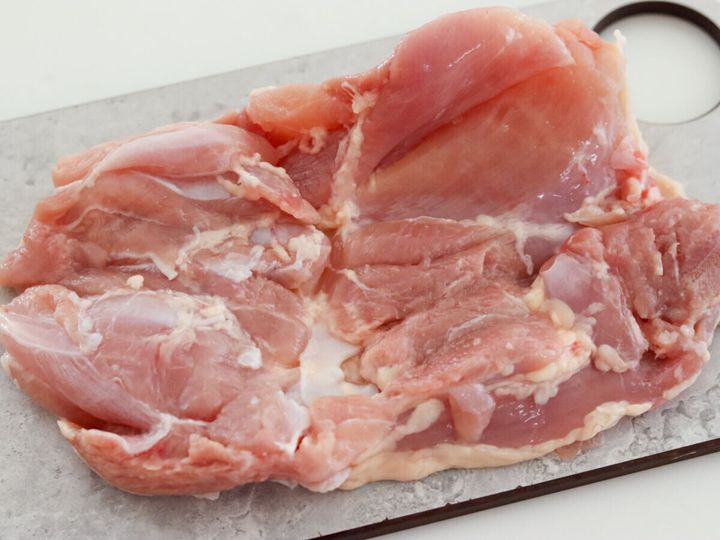 まな板の上に広げた生の鶏もも肉