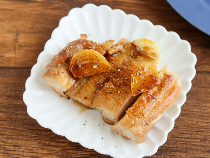 白い皿に盛ったにんにく山のもも肉に黒こしょうをふった完成写真