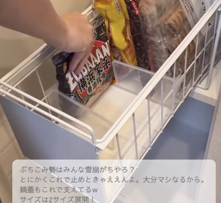 A person’s hand pulls a snack bag from a freezer drawer filled with bags and snacks on a white wire rack.