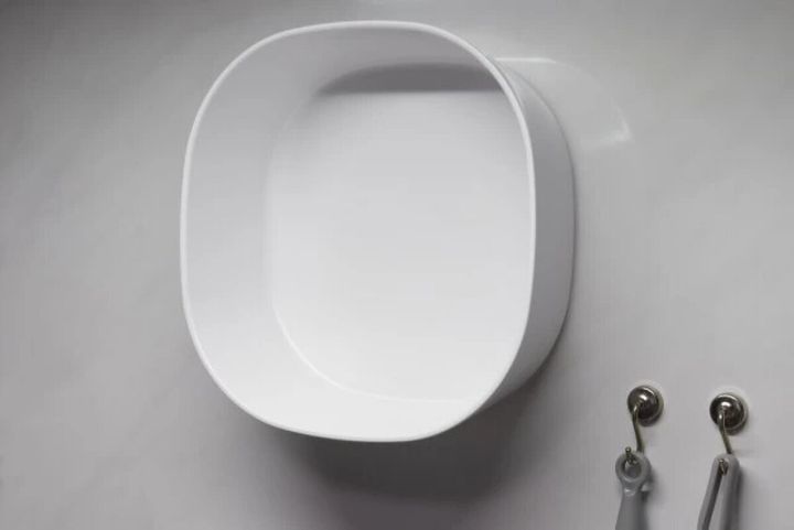 湯おけを浴室の壁面に貼り付けて収納する様子