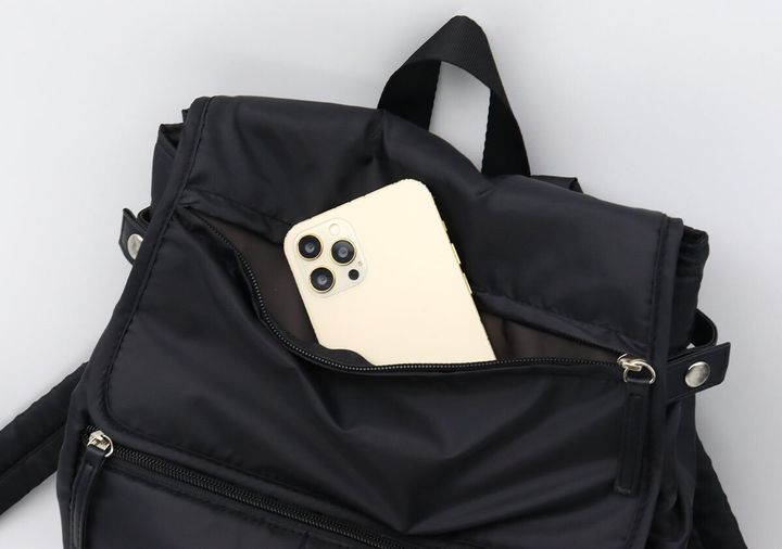 フラップ部分のポケットからスマートフォンを取り出している様子