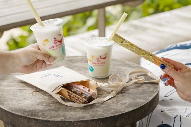 「海辺のアートdays」期間限定メニューの「アートな島シェイク」は、ひと口目で優しい島豆腐の味わいを感じることができる。「お散歩チュロス」は4種のチュロス＆かわいいサコッシュがセットに。その名の通り、お散歩しながら楽しむのもおすすめ