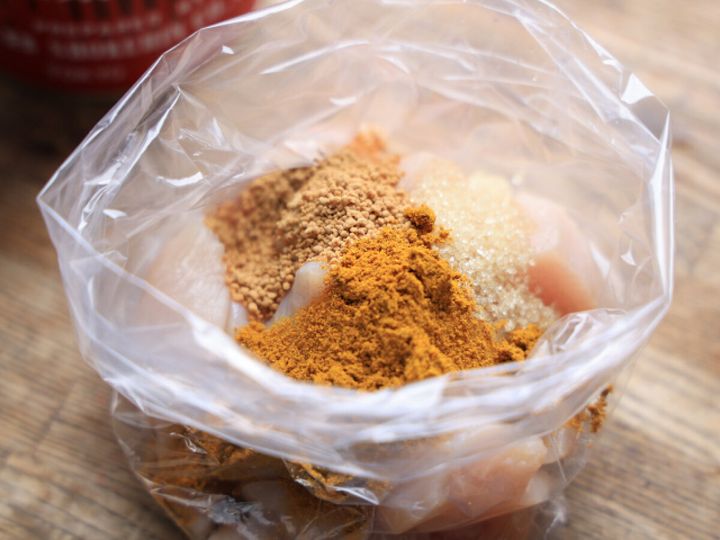 ビニール袋に入れた鶏むね肉にカレー粉・顆粒コンソメ・砂糖をのせた様子