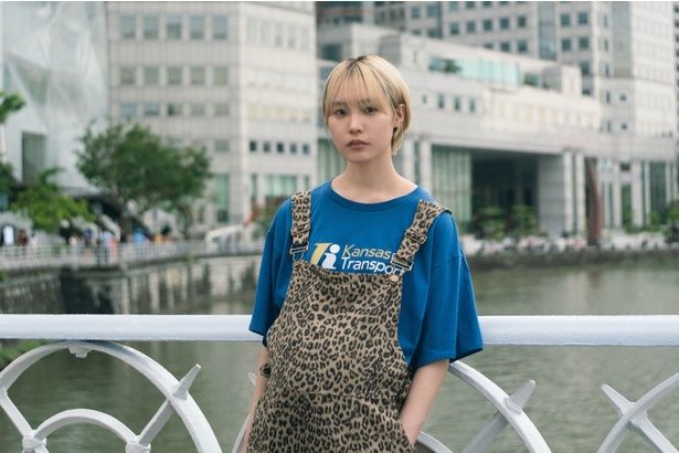 シンガポールの橋の上に立っている麻由 [c]2026「マジカル・シークレット・ツアー」製作委員会 