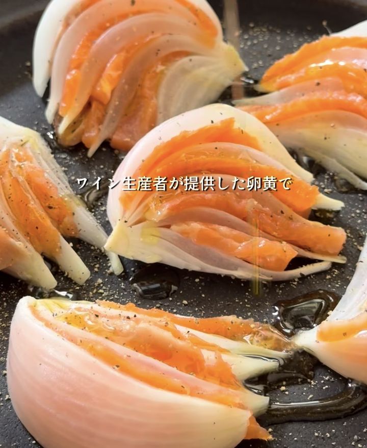 Salmon fillets wrapped in onion petals being sautéed in a frying pan.