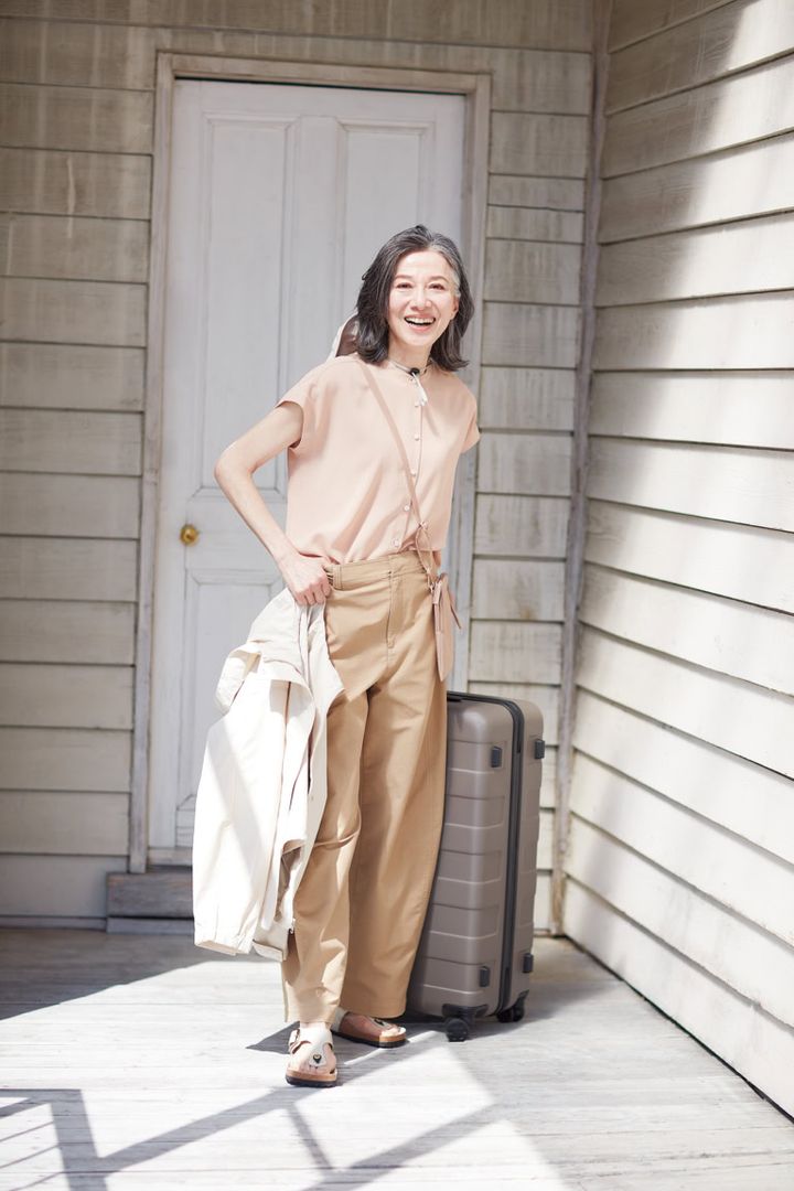 ブラウス¥3,990、手に持ったジャケット¥5,990、ミニサコッシュ¥1,290、スーツケース¥31,900／すべて無印良品（無印良品 銀座）、パンツ¥3,990／ユニクロ、ハット¥6,990／プラステ、シューズ¥28,600／ビルケンシュトック（ビルケンシュトック・ジャパン カスタマーサービス）