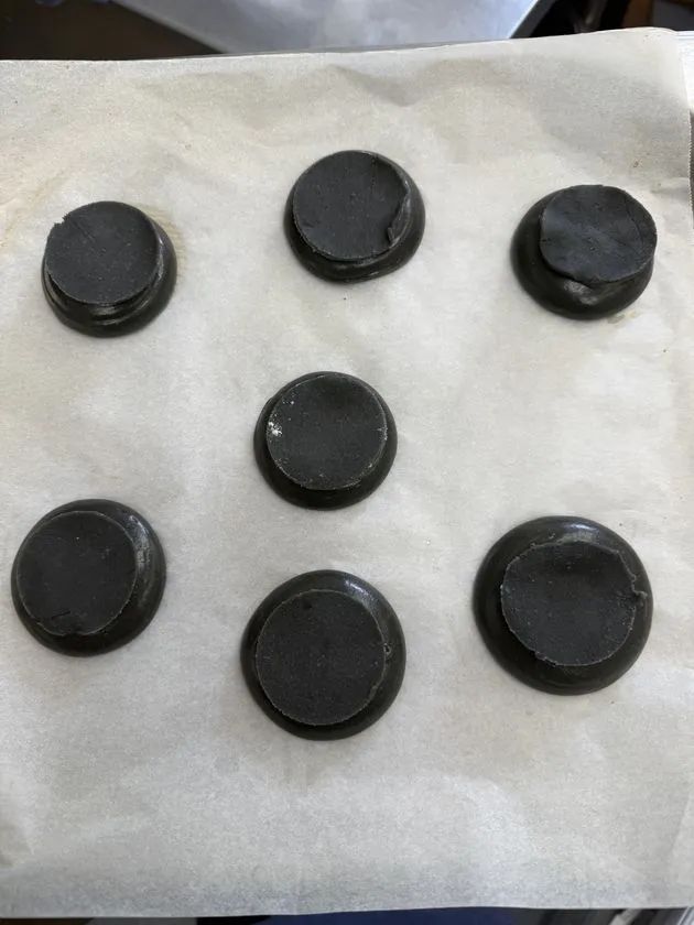 青いシュークリーム ORBIS BLUE の製造工程写真。黒いシュー生地を天板に並べた焼成前の状態が具体的に伝わる画像。