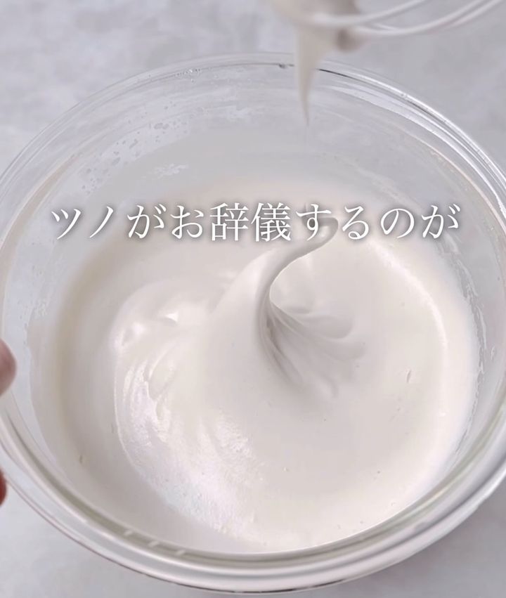 Whipped cream forming soft peaks in a glass bowl, whisk above; Japanese caption: ツノが お辞儀するのが