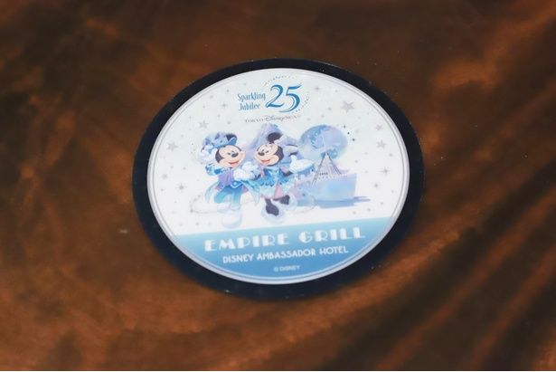 スペシャルドリンクに付いてくるオリジナルコースター。プロメテウス火山や豪華客船「S.S.コロンビア号」を背景に立つ、ミッキー&ミニーをデザイン