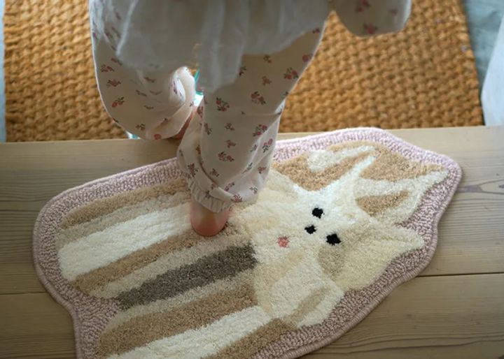 アイボリーとピンクふちの犬型シャギーラグに子どもが素足で乗っている使用シーン