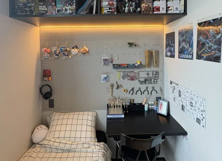 モデルハウス内の趣味部屋実例。ガンプラ・模型キットを飾る有孔ボード壁面収納とLED間接照明付き棚、製作用デスクを備えたホビースペース