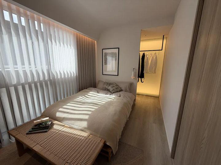 泉北ホームみのお第2展示場のモデルハウス主寝室。シングルベッド・バスケット素材のベンチ・奥にウォークインクローゼットが続く動線を自然光の差し込む様子とともに撮影