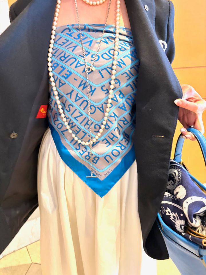 「エルメス」のスカーフをビスチェ風に巻いて、インナーに使うという大胆なアイデアが、「ドゥーズイエムクラス」の定番紺ブレを一気に個性的で華やかな印象に。 「スカーフの鮮やかなブルーカラーが、紺ブレの色に合っていると感じて、クルッと巻いてみました。クリップ同様、ちょっと遊び心で楽しんでいます」