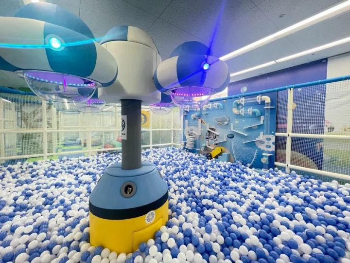 青と白のボールプール、UFO型LED照明付きアトラクション、宇宙とロボットの壁面装飾があるキッズエリア