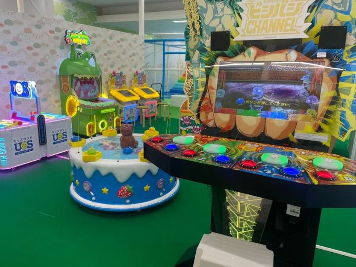 ビシバシCHANNELのボタン式体感ゲーム筐体、ケーキ型クレーンゲーム、カエルキャラクターのメダルゲーム機が並ぶゲームコーナー