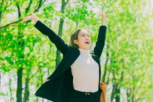 新緑の中で万歳する女性