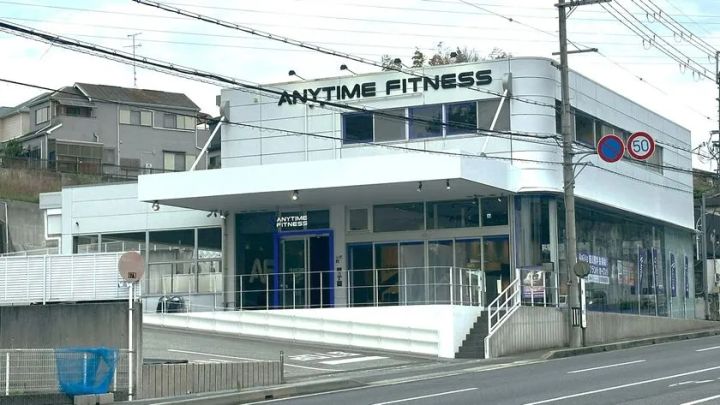 エニタイムフィットネス川西東畦野店の白い2階建て外観全景。幹線道路沿いに立地し、1階エントランスと大型ロゴサインが確認できる店舗写真