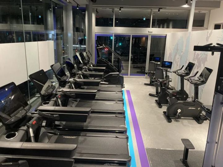 店内カーディオエリアの設備写真。LifeFitness製トレッドミル複数台とバイクマシンが整列し、モニター付き最新機器と窓際の開放的なレイアウトが確認できる
