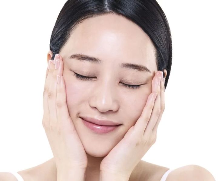 透明なオイルを頬へゆっくりと伸ばしている肌のクローズアップ