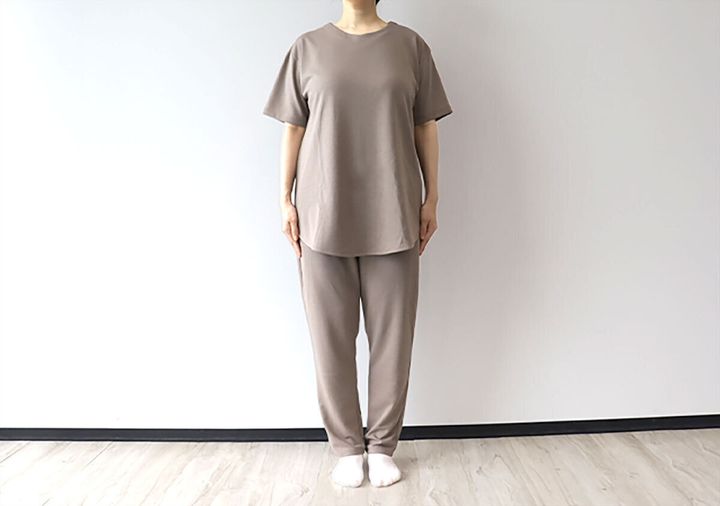 グレージュの半袖ロングチュニックとロングパンツの上下セットを着用した女性の正面全身