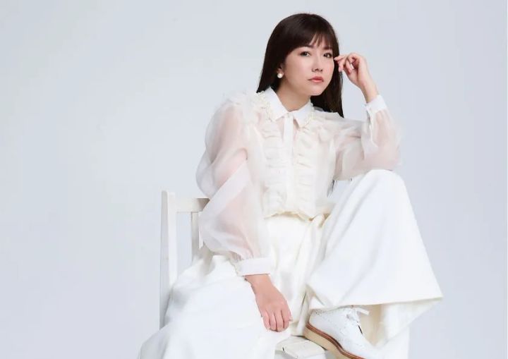 白いオーガンジーブラウスとワイドパンツ姿でフォーマルな宣材ポーズをとる島谷ひとみのスタジオポートレート
