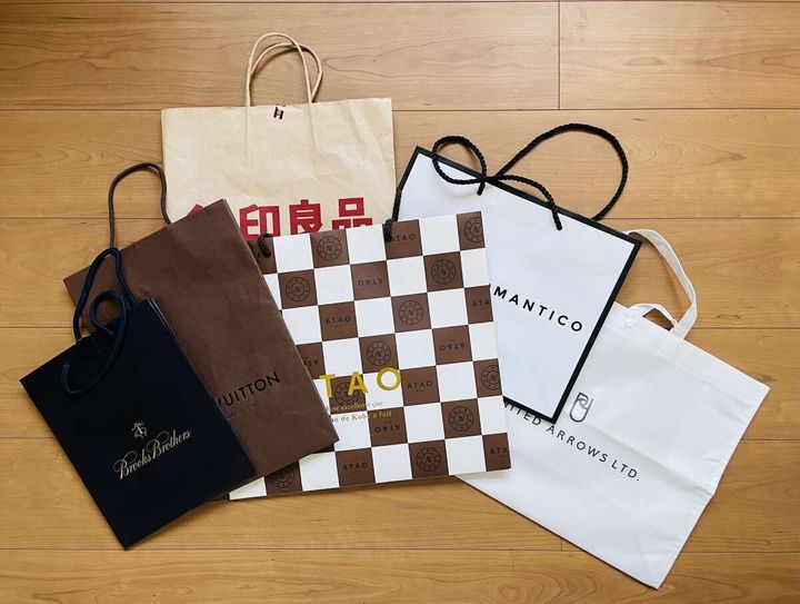 フローリングに並べられた様々なブランドの紙袋やショップ袋