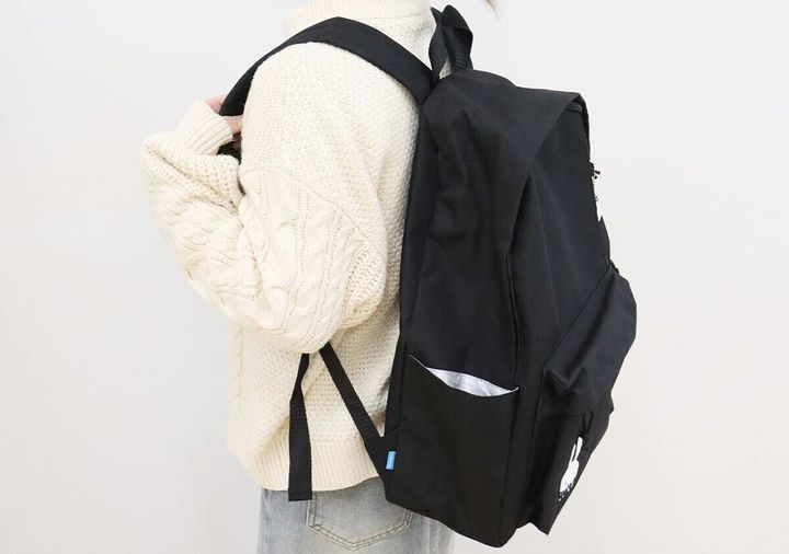 白いケーブルニットの女性がCUNE×smart黒バックパックを背負った後ろ姿