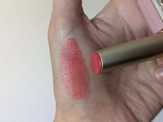 Peony Special Bookのメルティングクリームリップバーム02 Peach Syrupを手の甲にスウォッチしたようす。透け感のあるコーラルピンク