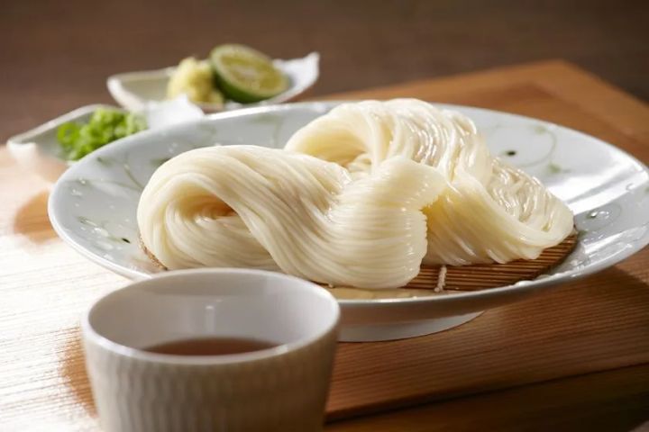 茹でた半田そうめんを白い楕円皿に盛り付け、竹すのこ・つゆ・すだち・薬味を添えた料理盛り付けショット