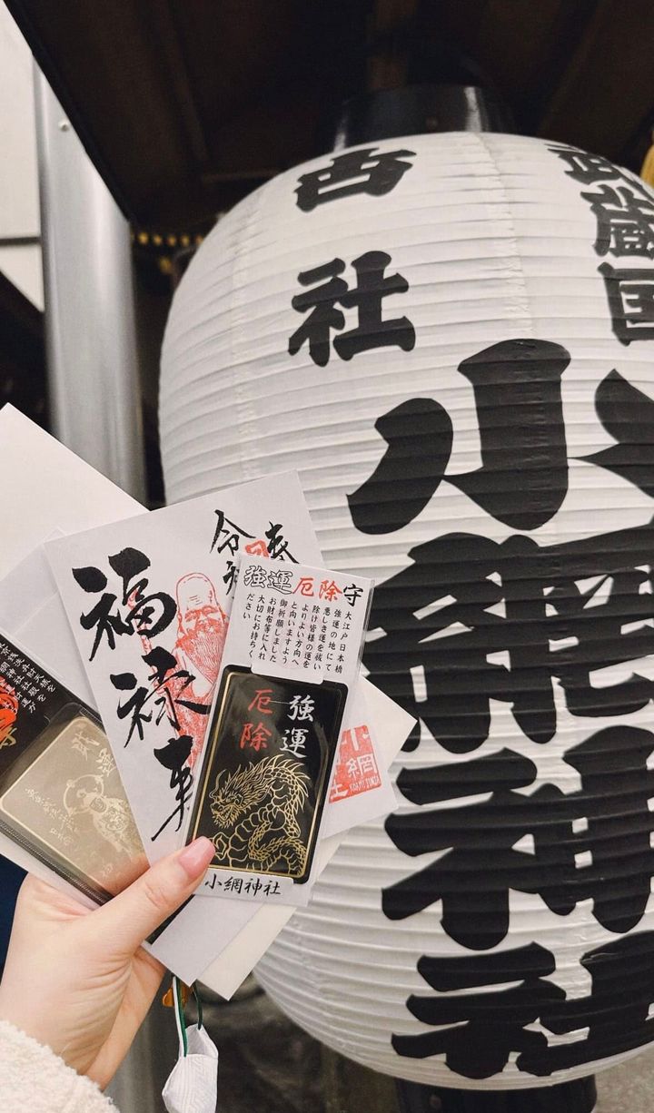 小網神社の提灯の前で、購入した厄除けのお守りを手に持っている平松さん。