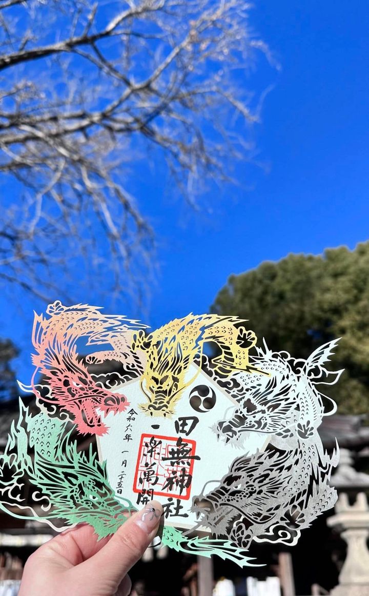 田無神社の境内。寒川神社の境内。購入した、龍が描かれている絵馬を手に持っている平松さん。