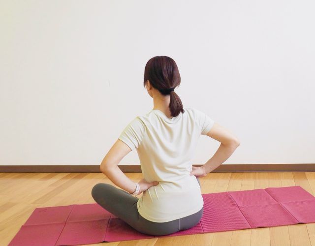 腰に手を当ててあぐらで座る女性