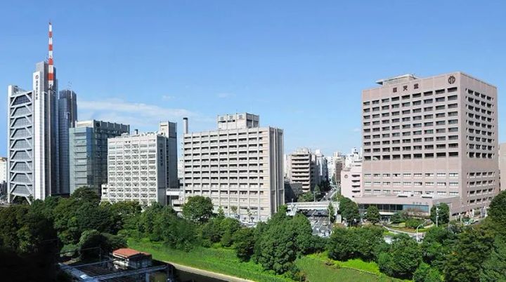 順天堂大学病院本院ビル群を中心に周辺の複数棟と緑地を俯瞰した外観写真。共同研究先の大学病院の規模と立地を示す