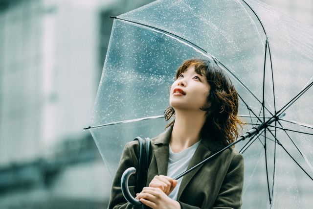 雨天 傘をさして空を見上げる女性