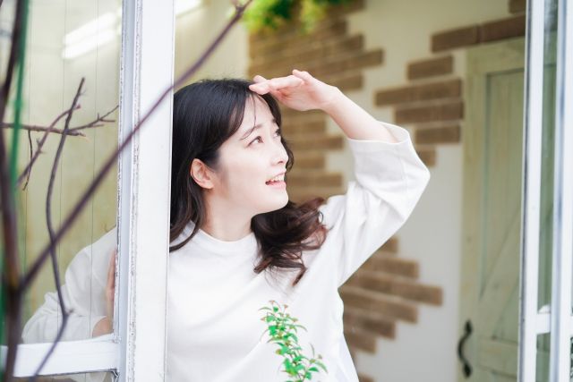 曇り空 窓から空を見上げる女性