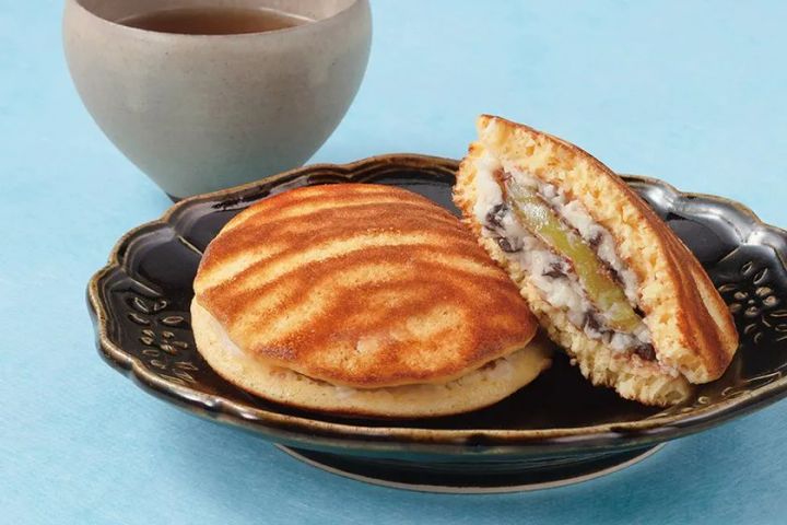 どら焼き2個を黒釉薬の皿に盛り、1個を断面カットして見せることでミントクリームとチョコチップの餡が確認できる構成。背景に湯呑みを配置