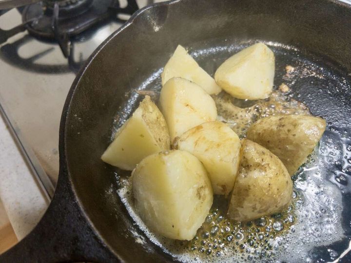 蒸し焼きにした新じゃがにバターとみりんを加えてスキレットで絡める様子